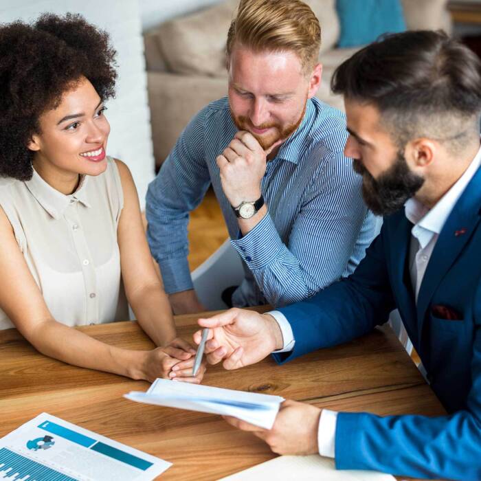 Investment and financial advisor sitting at a table meeting with a client couple discussing wealth management and financial planning