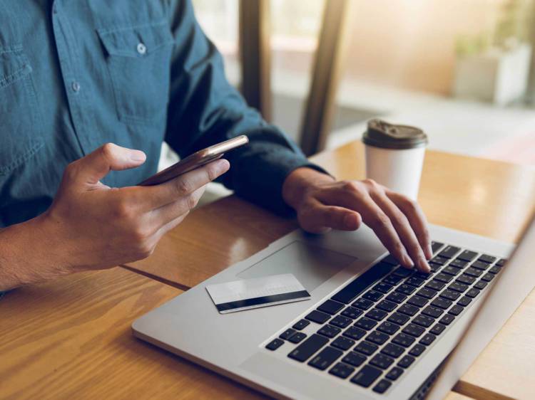 Client sitting at desk holding his phone with a financial card on his laptop