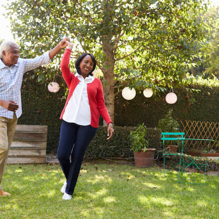 Retired elderly senior couple dancing in their backyard