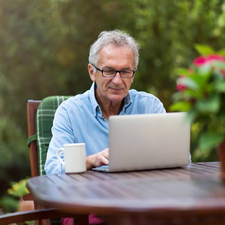 Financial client looking at his computer in his backyard setting reviewing his wealth management