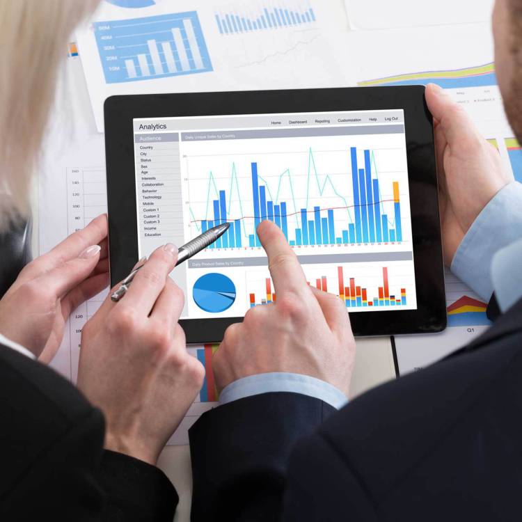 Fiduciary investors and financial advisors discussing the stock graph displayed on a tablet they are both holding