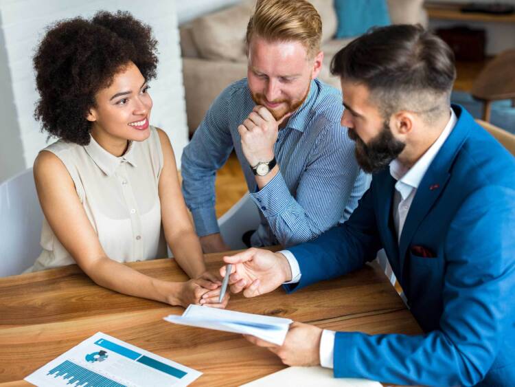 Investment and financial advisor sitting at a table meeting with a client couple discussing wealth management and financial planning