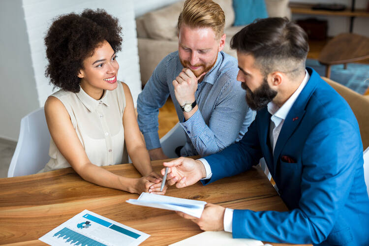 Investment and financial advisor sitting at a table meeting with a client couple discussing wealth management and financial planning