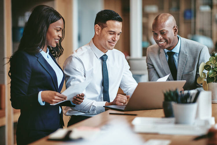 Fiduciary investment and financial advisors all looking at a laptop in office discussing financial matters