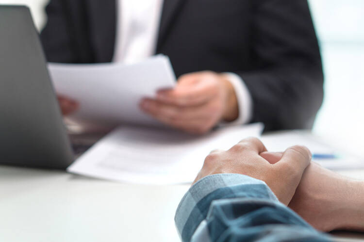 Fiduciary investment and financial advisor holding documents and reviewing financial matters with client who is sitting across the table