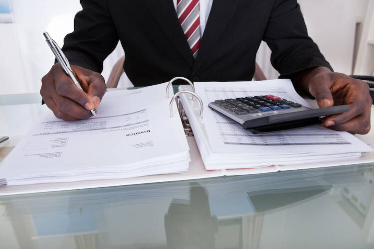 Fiduciary investment advisor holding a calculator and going over financial documents