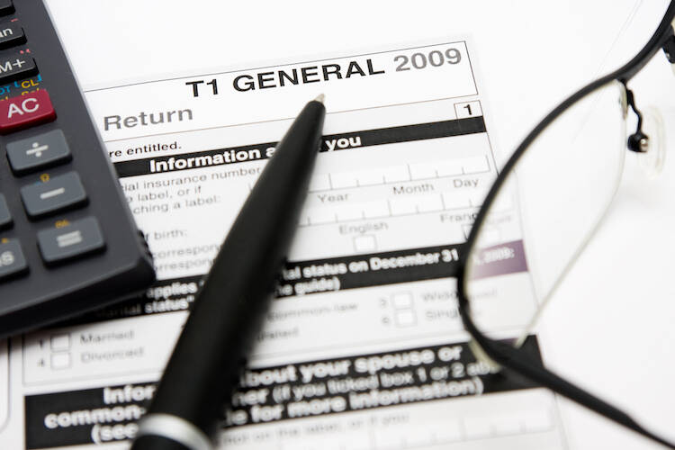 Pen, calculator and eye glasses sitting on top of Canadian tax return document