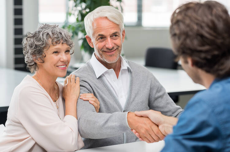 Happy senior couple with husband shaking hand with fiduciary investment and financial advisor