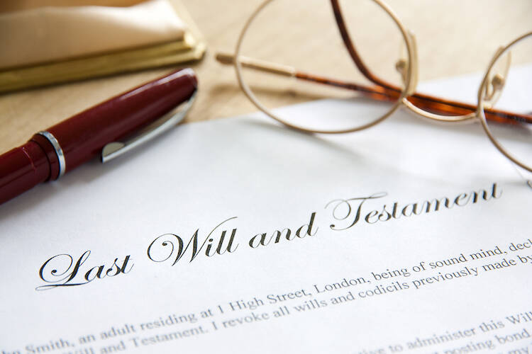 Piece of paper titled with the last will and testament on a table with a pen and eye glasses