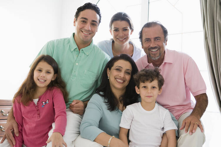 Family of two parents and four children sitting together happily
