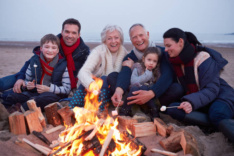 Multi Generation Family sitting around a campfire roasting marshmellow