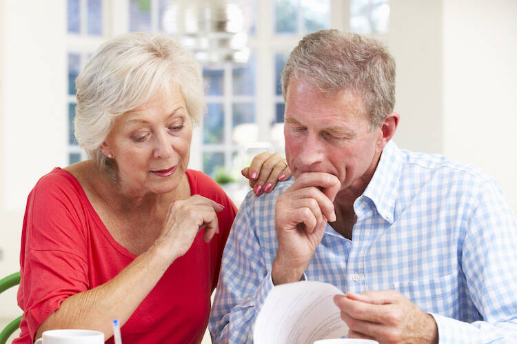 Retired couple reviewing financial documents about investing