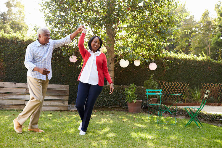 Retired elderly senior couple dancing in their backyard